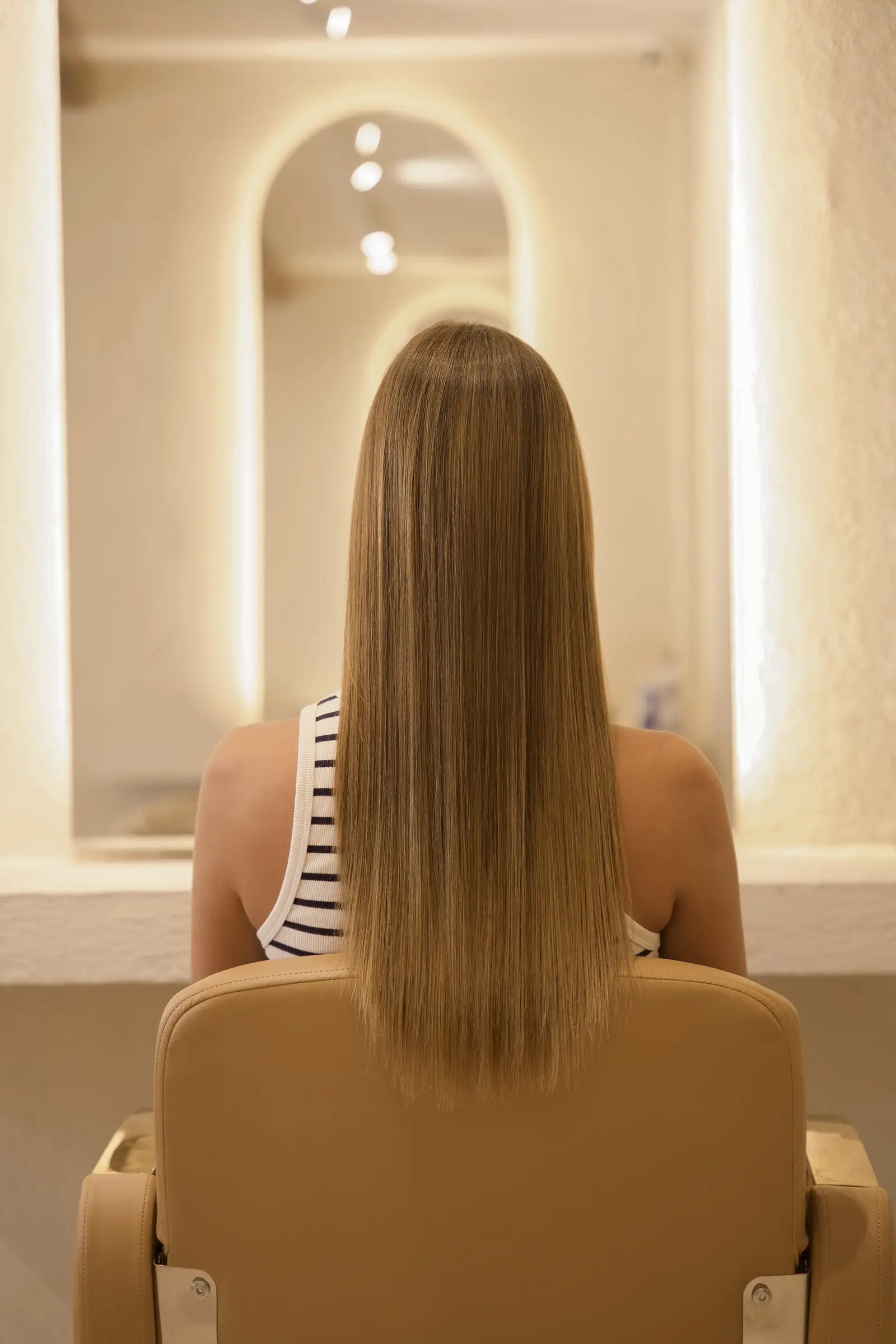 A blonde guest in the salon chair with long, sleek hair after her treatment at Day Hair Habit