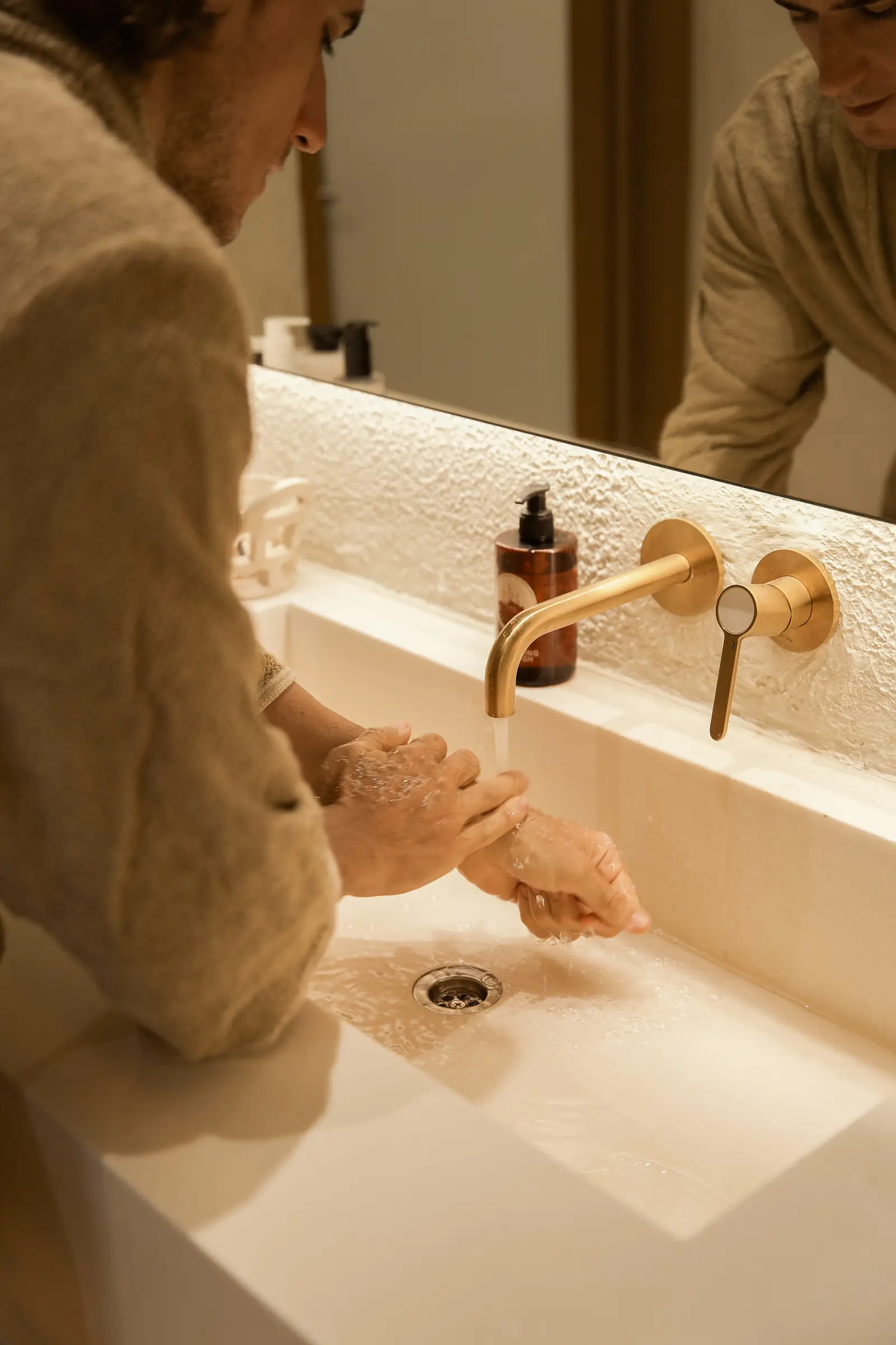 A guest in a bathrobe at the basin after his shower at Day Hair Habit
